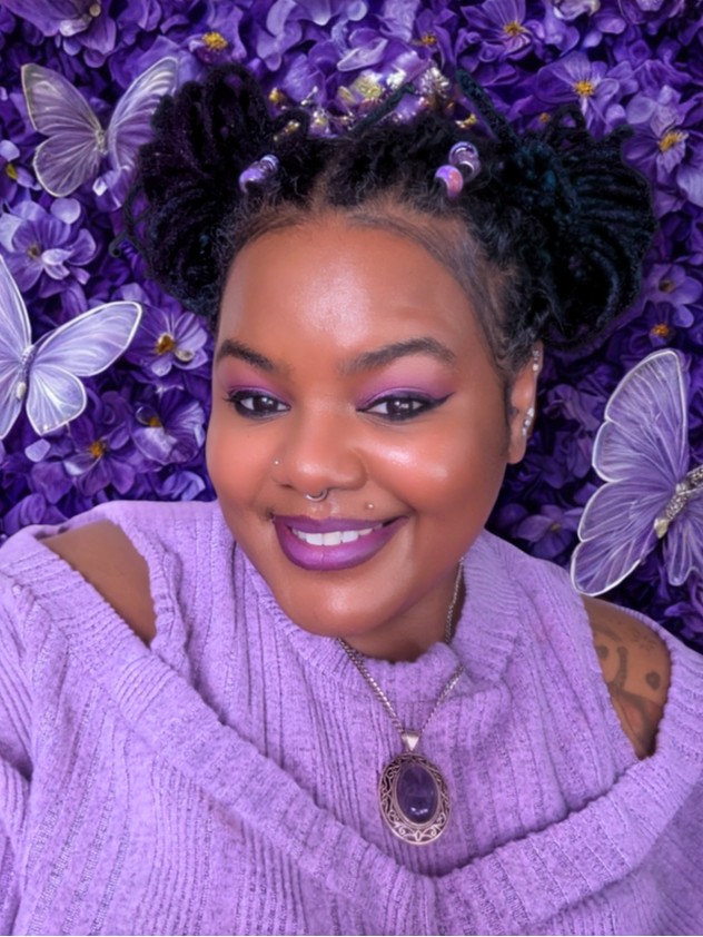Woman in a purple sweater with a decorative background of purple flowers and butterflies.